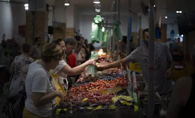 A woman buys fruit in a local market in Haifa, Israel, on Aug. 16, 2024. (AP Photo/Leo Correa)