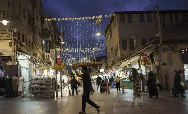 FILE - A man carry breads on a board over his head at the Mahane Yehuda market in Jerusalem, on March 6, 2024. (AP Photo/Leo Correa, File)