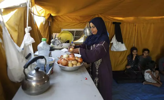 Majida Abu Jarad cooks in a tent camp, where she and her family now live after being displaced over five times since the start of the Israel-Hamas war, in Muwasi, Gaza Strip, Thursday, Sept. 12, 2024. (AP Photo/Abdel Kareem Hana)