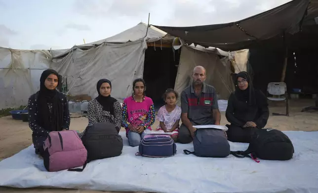 Members of the Abu Jarad family pose for a photo in their tent camp, where they now live after being displaced over five times since the start of the Israel-Hamas war, in Muwasi, Gaza Strip, Friday, Sept. 13, 2024. (AP Photo/Abdel Kareem Hana)