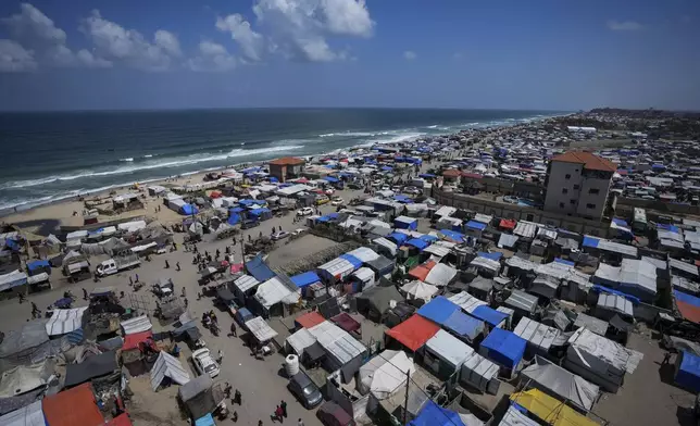 FILE - Palestinians displaced by the Israeli air and ground offensive on the Gaza Strip walk through a makeshift tent camp in Deir al Balah, Gaza, Sunday, May 12, 2024. (AP Photo/Abdel Kareem Hana, File)