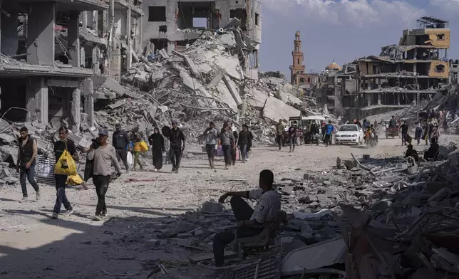 FILE - Palestinians walk through the destruction in the wake of an Israeli air and ground offensive in Khan Younis, southern Gaza Strip, Monday, April 8, 2024. (AP Photo/Fatima Shbair, File)