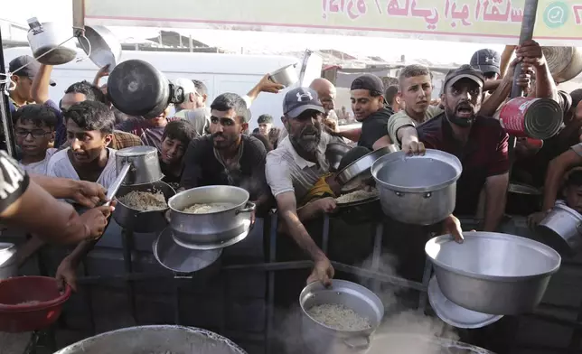 FILE - Palestinian men collect food aid ahead of the upcoming Eid al-Adha holiday in Khan Younis, Gaza Strip, on June 15, 2024. (AP Photo/Jehad Alshrafi, File)