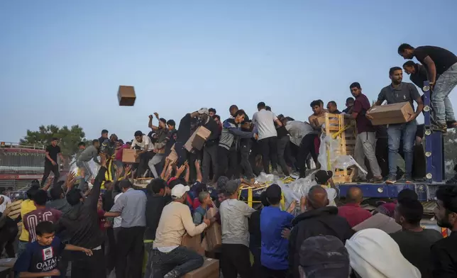 FILE - Palestinians are storming trucks loaded with humanitarian aid brought in through a new U.S.-built pier, in the central Gaza Strip, May 18, 2024. (AP Photo/Abdel Kareem Hana, File)