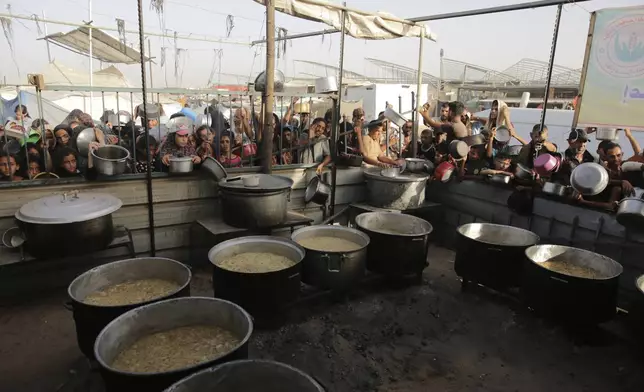 FILE - Palestinians collect food aid ahead of the upcoming Eid al-Adha holiday in Khan Younis, Gaza Strip, on June 15, 2024. (AP Photo/Jehad Alshrafi, File)