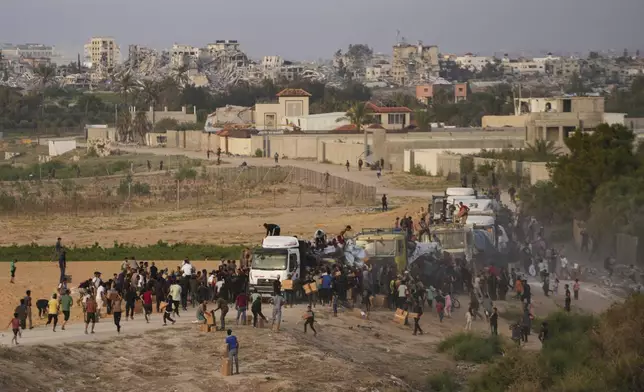 FILE - Palestinians are storming trucks loaded with humanitarian aid brought in through a new U.S.-built pier, in the central Gaza Strip, May 18, 2024. (AP Photo/Abdel Kareem Hana, File)