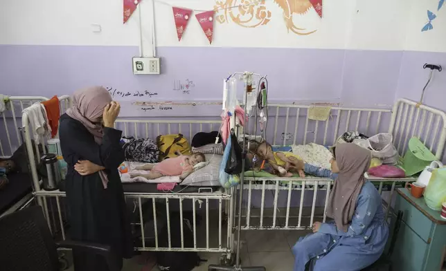 FILE - Amira Al-Jojo, left, stands beside her 10-month-old son, Yousef Al-Jojo, who suffers from malnutrition at Al-Aqsa Martyrs Hospital, where he is undergoing treatment, in Deir al-Balah in the central Gaza Strip on June 1, 2024. At right is Nuha Al-Khaldi and her child. (AP Photo/Jehad Alshrafi)