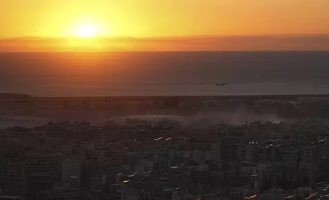 A Middle East Airlines airplane flies over Beirut as smoke rises from Israeli airstrikes in Dahiyeh, Beirut, Tuesday, Oct. 22, 2024. (AP Photo/Hassan Ammar)