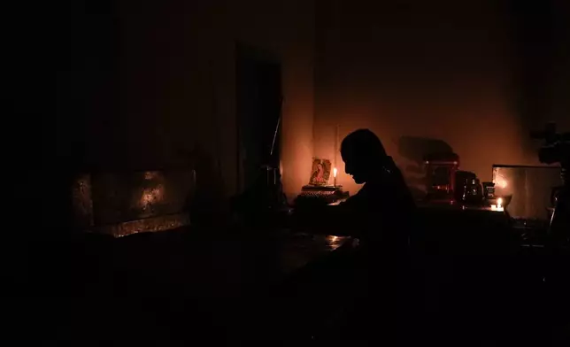 FILE - Monica Valiente waits for customers in her candle-lit bakery during a rolling blackout, in Quito, Ecuador, Oct. 15, 2024. (AP Photo/Dolores Ochoa, File)