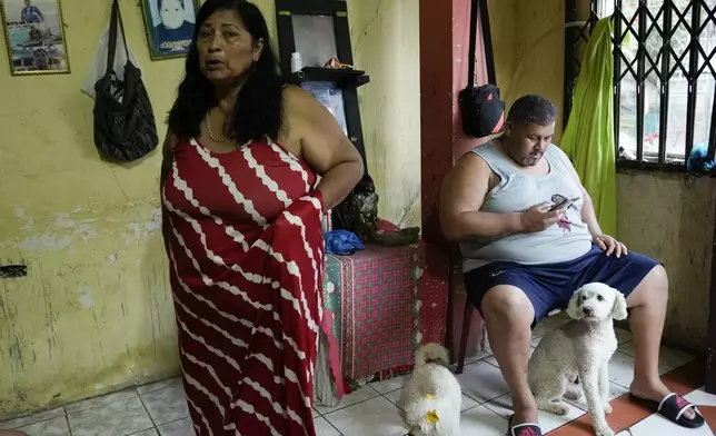 Maribel Montenegro talks about two of her sons who are in the U.S., one working and one in prison, as her eldest son Oswaldo Angulo sits nearby, in San Mateo, Ecuador, Wednesday, Sept. 25, 2024. (AP Photo/Dolores Ochoa)