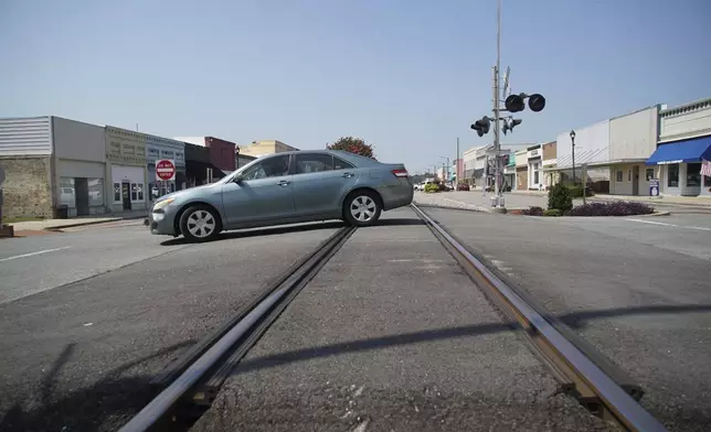 A car crosses the railroad tracks bisecting the main street in downtown Mount Olive, N.C., on Monday, July 15, 2024. (AP Photo/Allen G. Breed)