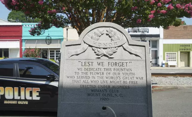 A police car passes a World War I memorial on Center Street in downtown Mount Olive, N.C., on Monday, July 15, 2024. (AP Photo/Allen G. Breed)