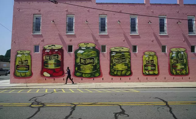 A man walks past a mural of various pickle products in Mount Olive, N.C., on Monday, July 15, 2024. (AP Photo/Allen G. Breed)