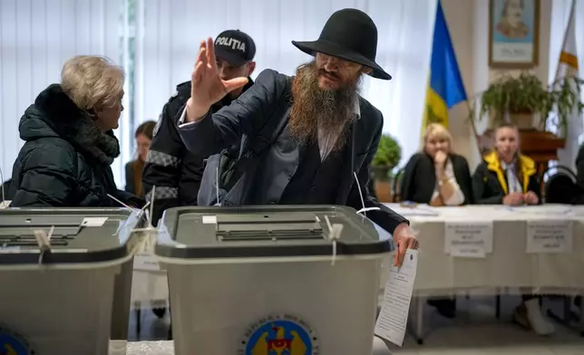 A man gestures after casting his vote in Chisinau, Moldova, Sunday, Oct. 20, 2024, during a presidential election and a referendum on whether to enshrine in the Constitution the country's path to European Union membership. (AP Photo/Vadim Ghirda)