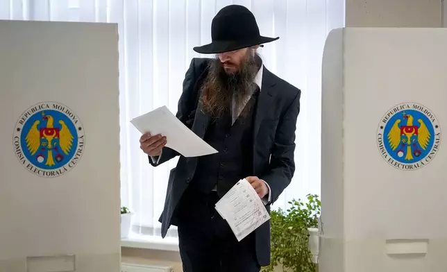 A man looks at candidates listed on the ballot in Chisinau, Moldova, Sunday, Oct. 20, 2024, during a presidential election and a referendum on whether to enshrine in the Constitution the country's path to European Union membership. (AP Photo/Vadim Ghirda)