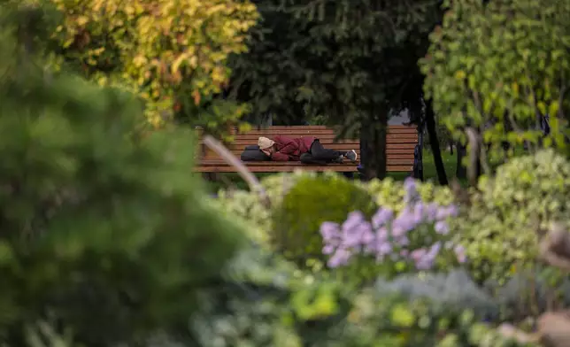 A man sleeps on a bench in a park in Chisinau, Moldova, Friday, Oct. 18, 2024, two days before a presidential election and a referendum on whether to enshrine in Moldova's Constitution its path to European Union membership. (AP Photo/Vadim Ghirda)