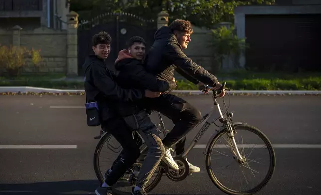 Young people ride a bicycle in Magdacesti, Moldova, Thursday, Oct. 17, 2024, ahead of a presidential election and a referendum of whether to enshrine in Moldova's Constitution its path to European Union membership taking place on Oct.20. (AP Photo/Vadim Ghirda)