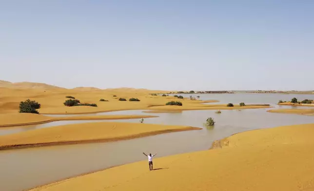 A man gestures as he walks on sand dunes next to a lake caused by heavy rainfall in the desert town of Merzouga, near Rachidia, southeastern Morocco, Wednesday, Oct. 2, 2024. (AP Photo)