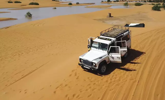 A vehicle transports tourists on sand dunes next to a lake caused by heavy rainfall in the desert town of Merzouga, near Rachidia, southeastern Morocco, Wednesday, Oct. 2, 2024. (AP Photo)