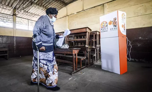 A woman carries a ballot at a polling station to cast her vote in general elections in Maputo, Mozambique, Wednesday, Oct. 9, 2024. (AP Photo/Carlos Equeio)