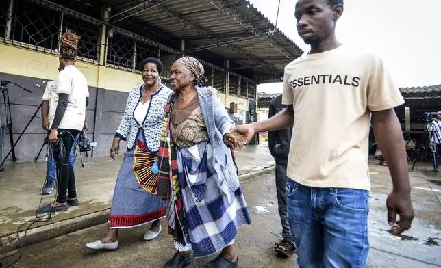 Women are helped as they arrive to cast their ballots at a polling station, in general elections in Maputo, Mozambique, Wednesday, Oct. 9, 2024. (AP Photo/Carlos Equeio)