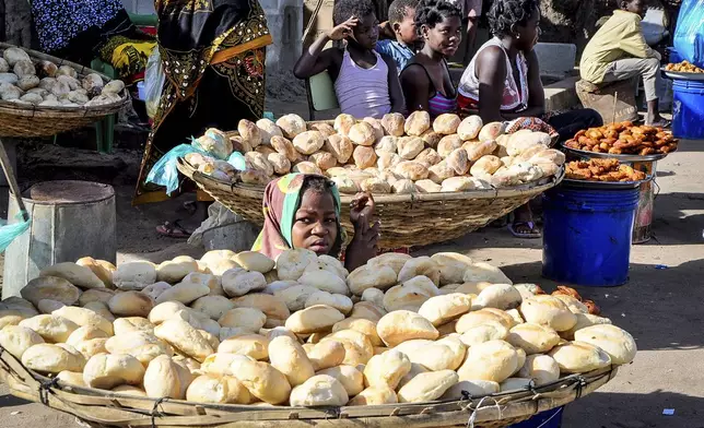 A woman sits between bread rolls in Maputo, Mozambique, Sunday, Oct. 6, 2024 ahead of elections to be held in the country. (AP Photo/Carlos Uqueio)