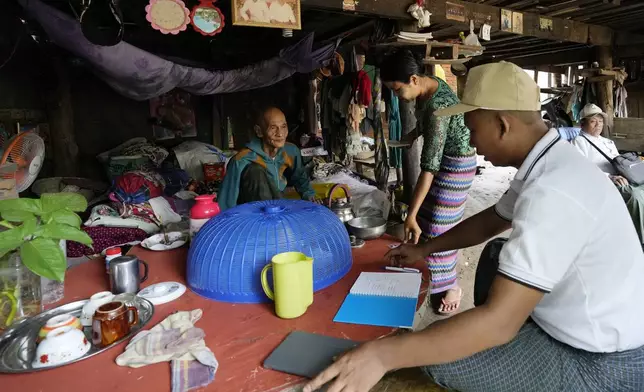 A census enumerator, foreground right, asks questions to a family in Naypyitaw, Myanmar Tuesday, Oct. 1, 2024 as the country holds a national census to compile voter lists for a general election and to analyze population and socioeconomic trends. (AP Photo/Aung Shine Oo)