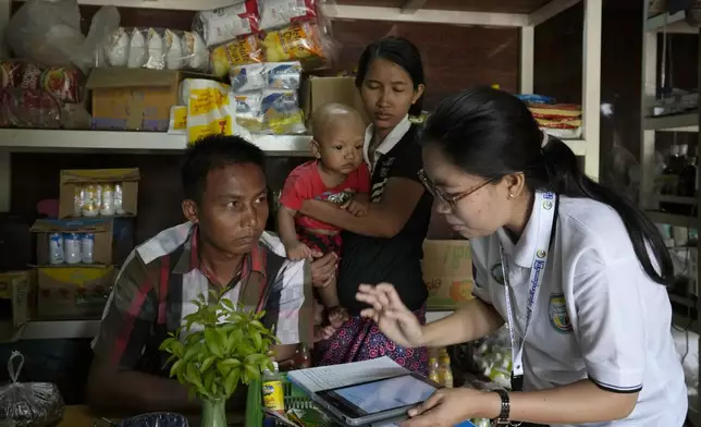 A census enumerator, right, asks questions to a family in Naypyitaw, Myanmar Tuesday, Oct. 1, 2024 as the country holds a national census to compile voter lists for a general election and to analyze population and socioeconomic trends. (AP Photo/Aung Shine Oo)