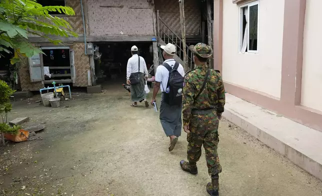 A soldiers provides security to census enumerators who collect information in Naypyitaw, Myanmar Tuesday, Oct. 1, 2024 as the country holds a national census to compile voter lists for a general election and to analyze population and socioeconomic trends. (AP Photo/Aung Shine Oo)