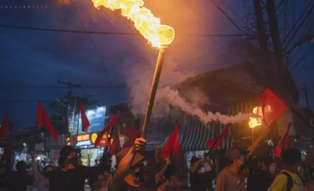 Pro-democracy protesters hold torches and flags during a flash mob rally to protest against Myanmar's military-government in Yangon, Myanmar on Sept.19, 2024. (Anti-Junta Alliance Yangon via AP)