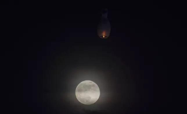 A supermoon rises while a hot-air balloon fly during the full moon day of Thadingyut, the end of Buddhist Lent, Thursday, Oct. 17, 2024, in Yangon, Myanmar. (AP Photo/Thein Zaw)