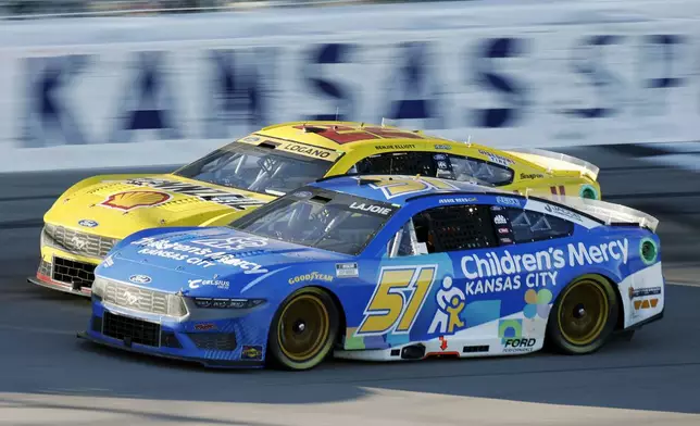 Corey LaJoie (51) and Joey Logano (22) race side-by-side as the head down the front straightaway during a NASCAR Cup Series auto race at Kansas Speedway in Kansas City, Kan., Sunday, Sept. 29, 2024. (AP Photo/Colin E. Braley)