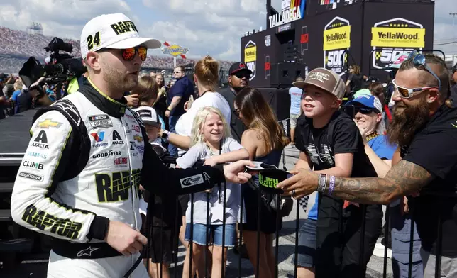 Driver William Byron signs an autograph before a NASCAR Cup Series auto race at Talladega Superspeedway, Sunday, Oct. 6, 2024, in Talladega, Ala. (AP Photo/ Butch Dill)