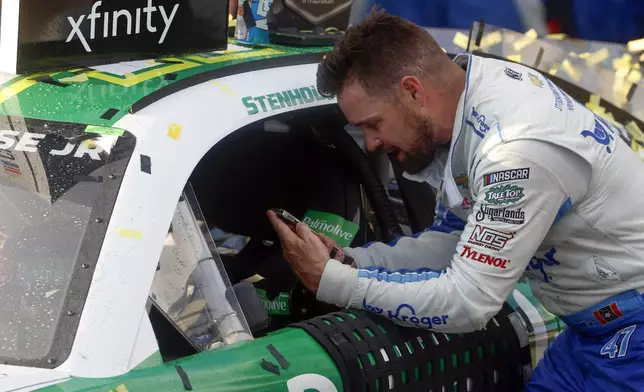 Driver Ricky Stenhouse Jr. talks with his wife and son on the phone as he celebrates in Victory Lane after a NASCAR Cup Series auto race at Talladega Superspeedway, Sunday, Oct. 6, 2024, in Talladega, Ala. (AP Photo/ Butch Dill)