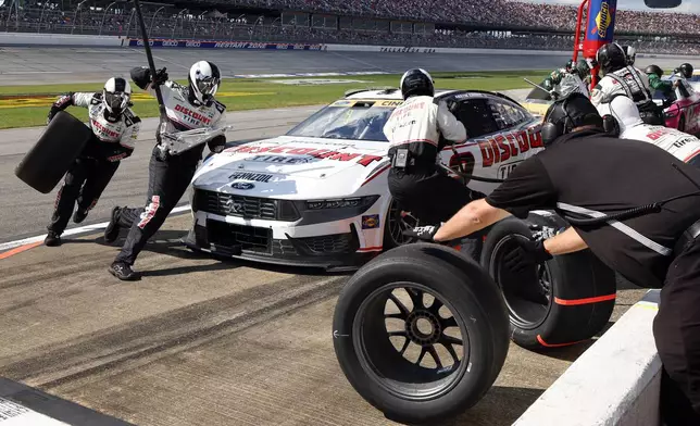 Crew members for driver Austin Cindric change tires during a NASCAR Cup Series auto race at Talladega Superspeedway, Sunday, Oct. 6, 2024, in Talladega, Ala. (AP Photo/ Butch Dill)