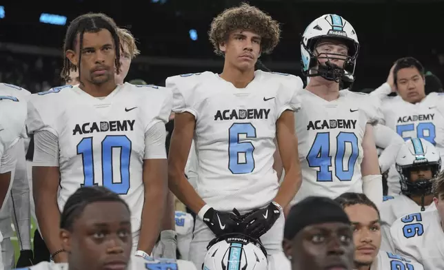 NFL Academy player Rafael Varona Blackstad, center, listens to the coach after a football game between the NFL Academy team and De La Salle High School, Tuesday, Oct. 8, 2024, in London. (AP Photo/Kin Cheung)