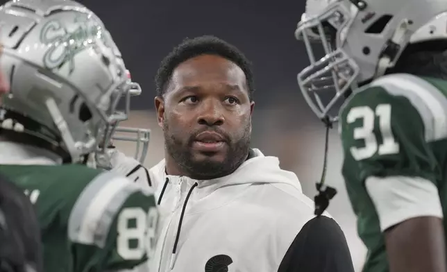 De La Salle High School coach and former NFL running back Maurice Jones-Drew, center, talks to his team during a football game between the NFL Academy team and De La Salle high school, Tuesday, Oct. 8, 2024, in London. (AP Photo/Kin Cheung)