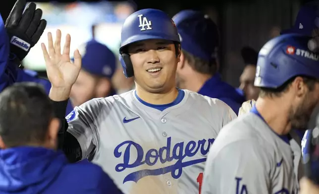 Los Angeles Dodgers' Shohei Ohtani celebrates in the dugout after scoring on a double by Mookie Betts during the fourth inning in Game 4 of a baseball NL Championship Series against the New York Mets, Thursday, Oct. 17, 2024, in New York. (AP Photo/Frank Franklin II)