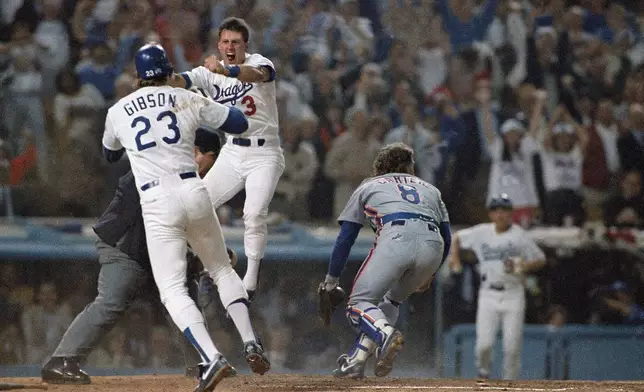 FILE - Los Angeles Dodgers second baseman Steve Sax (3) celebrates with teammate Kirk Gibson (23) after Sax scored in the second inning of Game 2 of the National League playoffs at Los Angeles, Oct. 5, 1988. New York Mets catcher Gary Carter (8) is at right. (AP Photo/Reed Saxon, File)