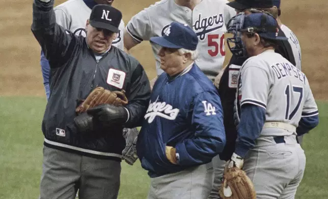 FILE - Umpire crew chief Harry Wendelstedt, left, signals the ejection of Los Angeles Dodgers pitcher Jay Howell, rear right, after a possible illegal substance was found in Howell's glove as as Los Angeles Dodgers manager Tommy Lasorda looks on, front center, in the eighth inning of a playoff game against the New York Mets in New York, Oct. 8, 1988. The rest of the players are unidentified. (AP Photo/Bill Kostroun, File)