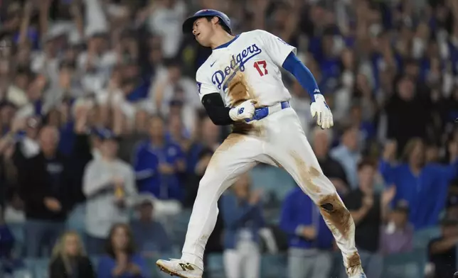 Los Angeles Dodgers' Shohei Ohtani celebrates after scoring on a single by Freddie Freeman against the New York Mets during the fourth inning in Game 1 of a baseball NL Championship Series, Sunday, Oct. 13, 2024, in Los Angeles. (AP Photo/Gregory Bull)