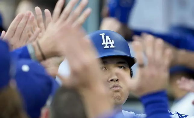 Los Angeles Dodgers' Shohei Ohtani celebrates in the dugout after scoring on a double by Tommy Edman during the first inning in Game 6 of a baseball NL Championship Series against the New York Mets, Sunday, Oct. 20, 2024, in Los Angeles. (AP Photo/Ashley Landis)