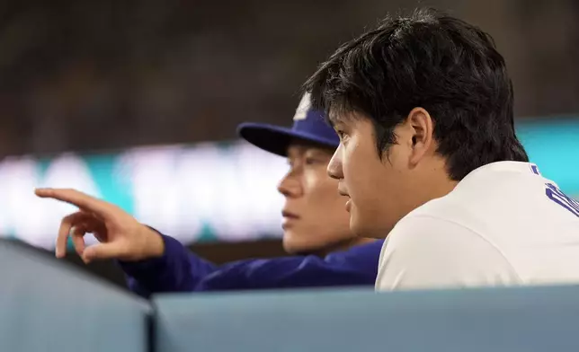 Los Angeles Dodgers' Shohei Ohtani and pitcher Yoshinobu Yamamoto watch during the sixth inning in Game 6 of a baseball NL Championship Series against the New York Mets, Sunday, Oct. 20, 2024, in Los Angeles. (AP Photo/Ashley Landis)