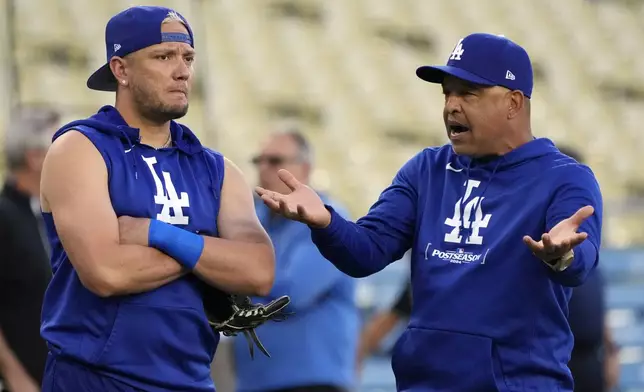 Los Angeles Dodgers' Miguel Rojas, left, talks with manager Dave Roberts during practice in preparation for Game 1 of a baseball NL Championship Series against the New York Mets, Saturday, Oct. 12, 2024, in Los Angeles. (AP Photo/Mark J. Terrill)