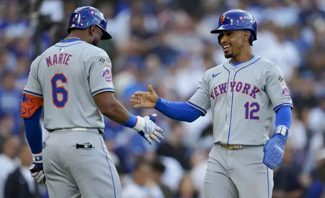 New York Mets' Francisco Lindor celebrates with Starling Marte after scoring on a throwing error by Los Angeles Dodgers second baseman Chris Taylor during the first inning in Game 6 of a baseball NL Championship Series, Sunday, Oct. 20, 2024, in Los Angeles. (AP Photo/Julio Cortez)