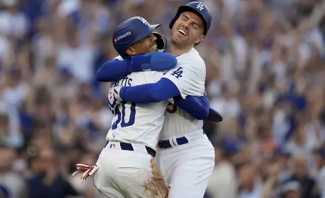 Los Angeles Dodgers' Freddie Freeman, right, and Mookie Betts celebrate after they scored on a single by Max Muncy during the first inning in Game 1 of a baseball NL Championship Series against the New York Mets, Sunday, Oct. 13, 2024, in Los Angeles. (AP Photo/Gregory Bull)