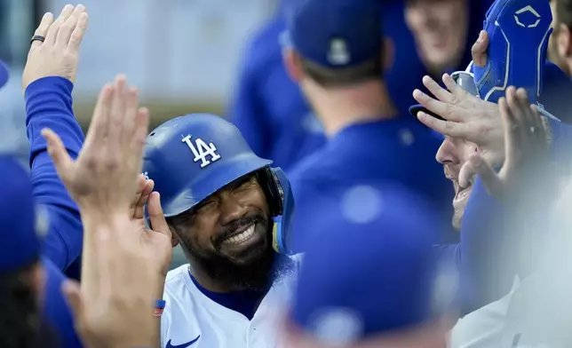 Los Angeles Dodgers' Teoscar Hernández celebrates in the dugout after scoring on a double by Tommy Edman against the New York Mets during the first inning in Game 6 of a baseball NL Championship Series, Sunday, Oct. 20, 2024, in Los Angeles. (AP Photo/Ashley Landis)