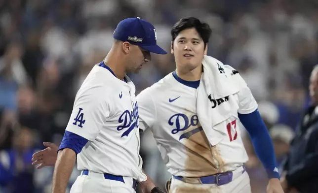 Los Angeles Dodgers pitcher Jack Flaherty, left, is greeted by Shohei Ohtani as he returns to the dugout during the seventh inning in Game 1 of a baseball NL Championship Series against the New York Mets, Sunday, Oct. 13, 2024, in Los Angeles. (AP Photo/Ashley Landis)