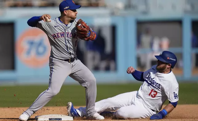 New York Mets second baseman Jose Iglesias, left, throws over Los Angeles Dodgers' Max Muncy to complete a double play on a ground ball from Kiké Hernández during the sixth inning in Game 2 of a baseball NL Championship Series, Monday, Oct. 14, 2024, in Los Angeles. (AP Photo/Gregory Bull)