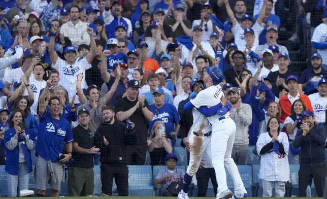 Los Angeles Dodgers' Freddie Freeman, right, and Mookie Betts celebrate after they scored on a single by Max Muncy during the first inning in Game 1 of a baseball NL Championship Series against the New York Mets, Sunday, Oct. 13, 2024, in Los Angeles. (AP Photo/Mark J. Terrill)